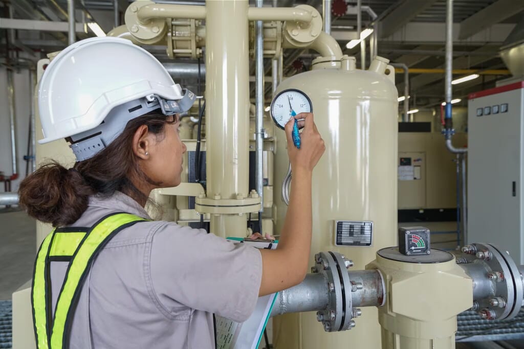 Technician performing routine maintenance on an industrial rotary screw air compressor.